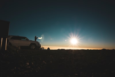There is a white car parked at sunset
